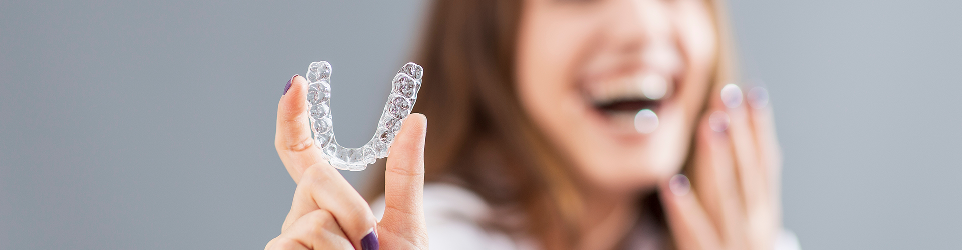 smiling woman holding clear aligner